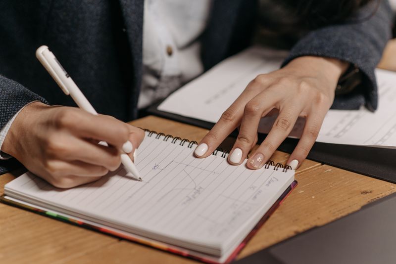 Close-up of someone writing detailed notes — the foundation of a credible bid response