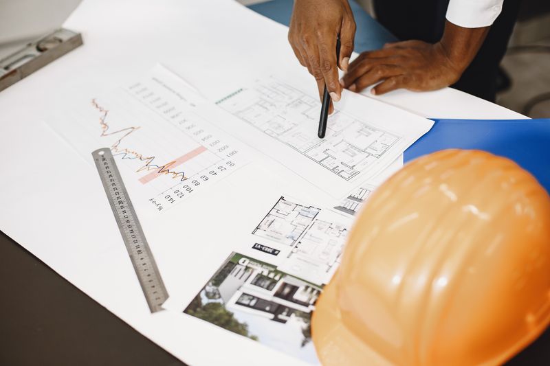 Architect reviewing blueprints and technical drawings on a desk — the raw material of a social value commitment