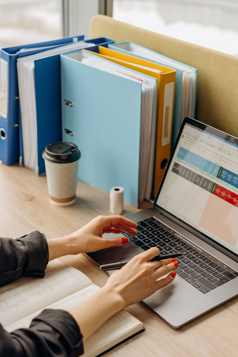 Hands typing a bid response on a laptop with documents on the desk